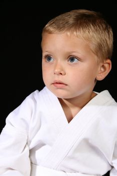 Young boy wearing his karate uniform on a black background
