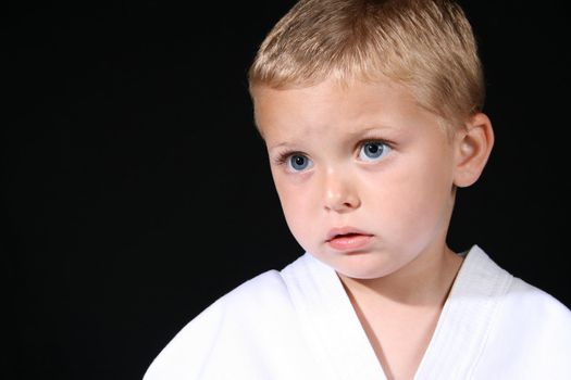Young boy wearing his karate uniform on a black background
