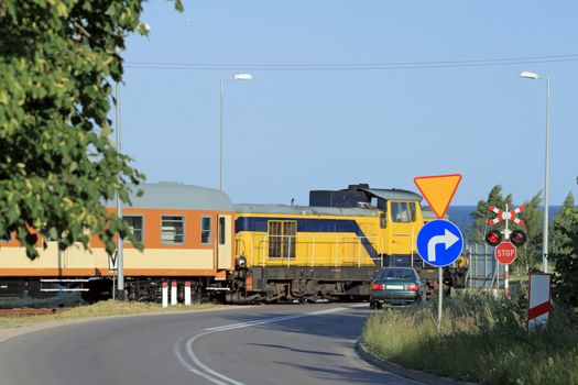 Passenger train passing the railroad crossing with the road
