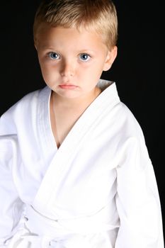 Young boy wearing his karate uniform on a black background
