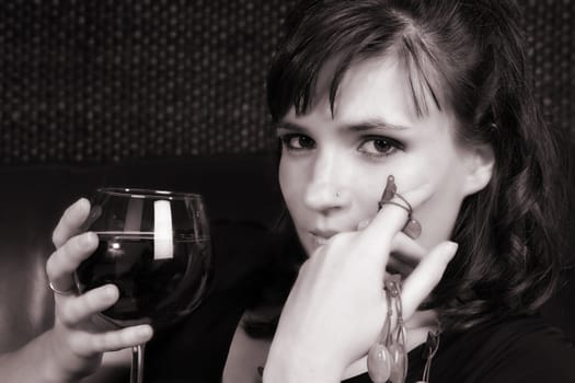 Female model with intense eyes holding a glass of red wine