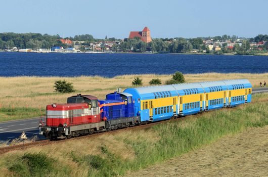 Double deck train hauled by the two diesel locomotives against baltic sea and coastal line
