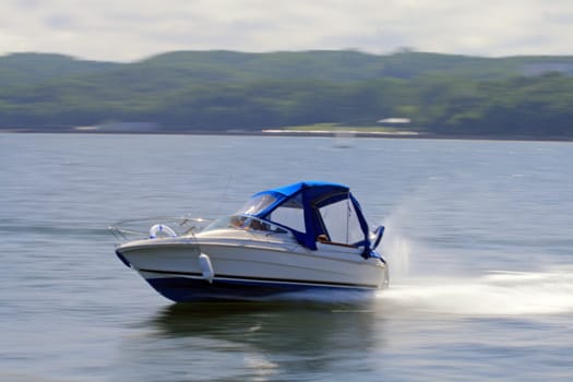 Motorboat riding fast on the bay with motion blurred background
