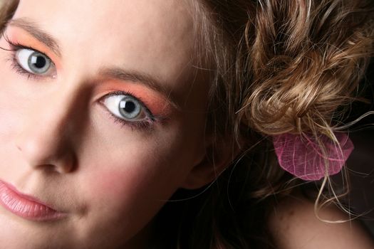 Close up of a beautiful blond with blue eyes and flower in her hair