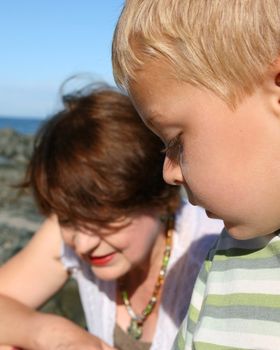 Beatiful grandmother and grandson playing on the beach