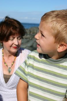 Beatiful grandmother and grandson playing on the beach