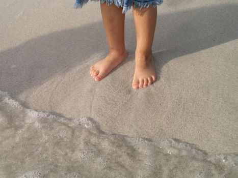 childs feets and breaking waves