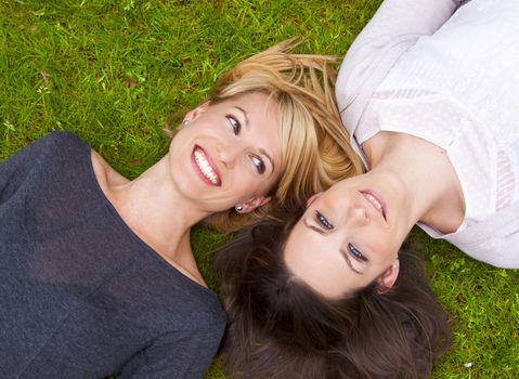 Two beautiful girls lying in the grass and laughing.