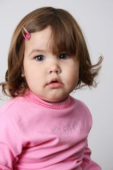 Toddler girl with chubby cheeks wearing a pink top 