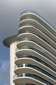 Large building with many floors, against a cloudy background