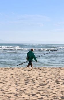 Fisherman walking on the beach after a days fishing