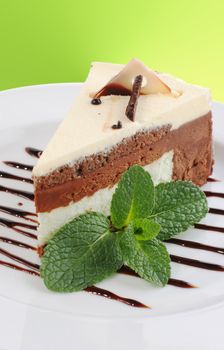 A piece of cake with a sprig of mint is on a plate.