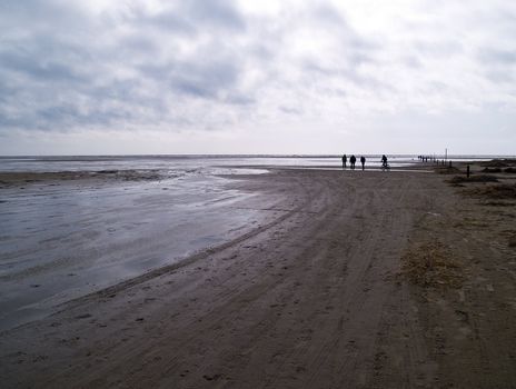 People having awalk on a beach on a cloudy winter day