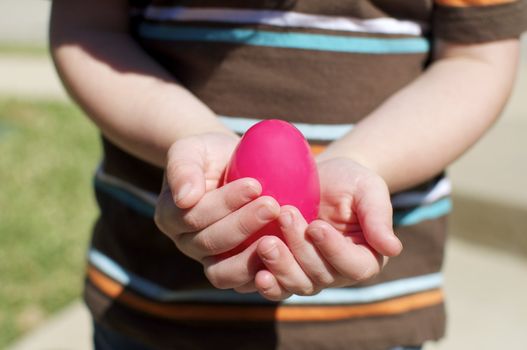 A small boy holds an easter egg in his little hands.