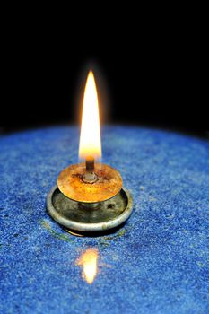 Close up of the flame of an oil lamp, on a black background. Space for text on the background.