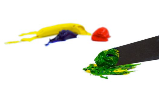 Yellow, blue, and red paint blobs being mixed by an artiists pallete knife