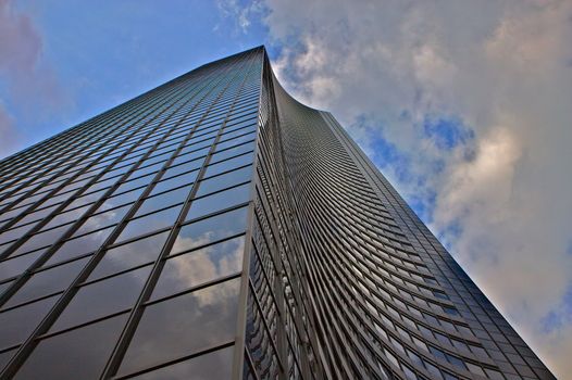 Close up of building with futuristic curved wall against a blue and cloudy sky