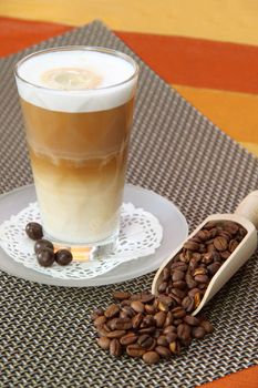 Latte Macchiato in glass with coffee grain on brown background
