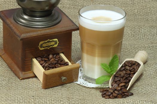 Latte Macchiato in glass with coffee grain on brown background