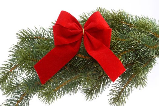 Red gift ribbon on fir tree branch on a white background. Close up. Christmas decoration.