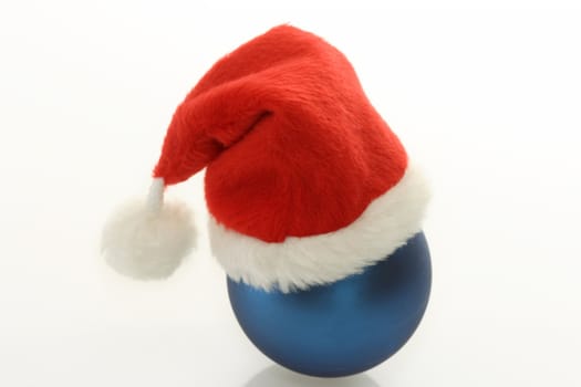 Christmas ball with santa claus cap  on bright background. Shot in studio.