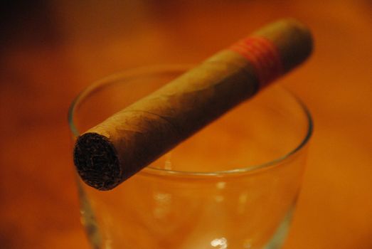 A cigar balancing on a glass.