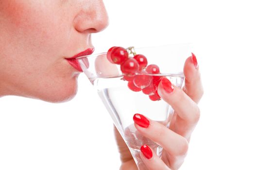 Woman mouth drinking from a cocktail glass decorated with red berries