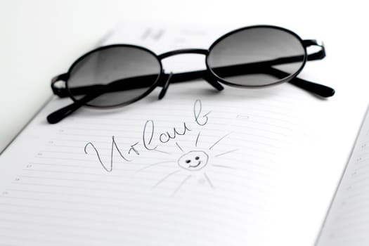 A notebook with the note "vacation" and sunglasses on top
