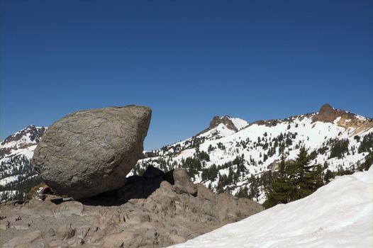 Precarious large boulder balanced with Lassen Mountain range in background