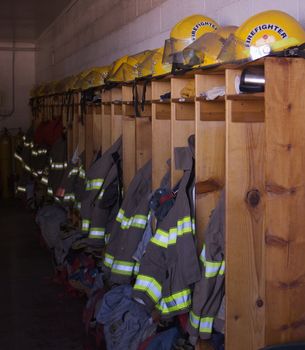 A row of lockers in a firehouse with jackets and helmets