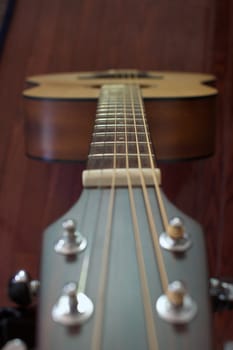 Guitar neck and strings looking from the head towards the body with soft focus at higher angle
