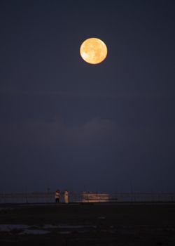 mothers baby sitting under a full moon at dawn