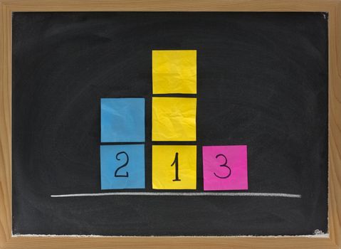 concept of three level podium to honor medalists in sporting events presented with sticky notes on blackboard