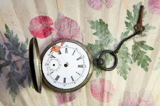 old pocket watch on handmade paper with leaves