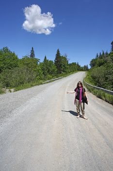 A beautiful brunette hitch-hiking on a country dirt road.