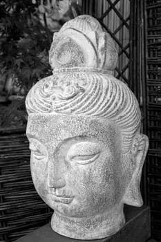 Black and white buda head statue situated in a garden