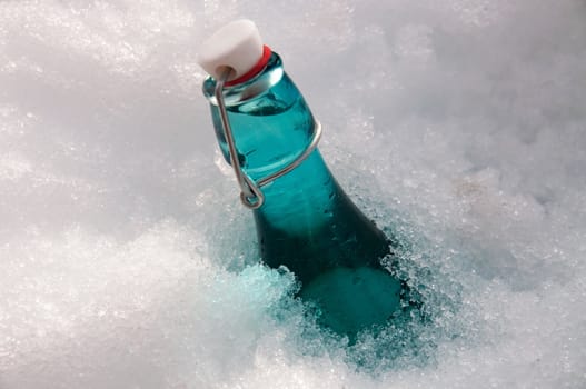A turquoise bottle with water buried in snow
