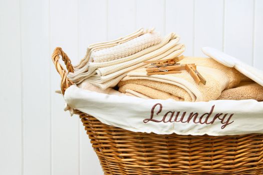 Clean towels in wicker basket with white wood background