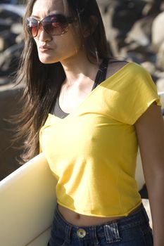 An asian surfer woman wearing a yellow top and jean skirt.