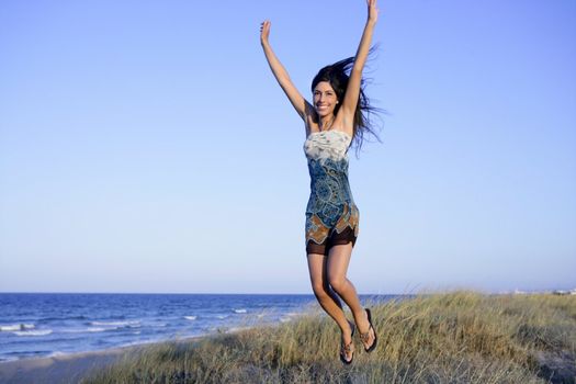 Beautiful brunette jumping in the summer blue beach