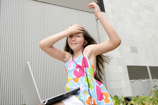Beautiful brunette little girl teen expression with laptop city outdoor