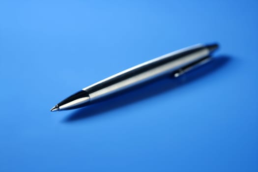 Single simple steel roller pen closeup over blue background