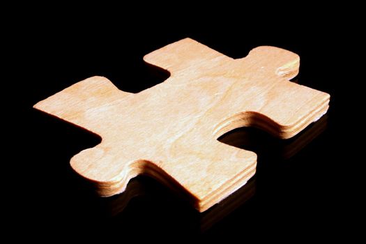 A large wooden puzzle piece on a black surface