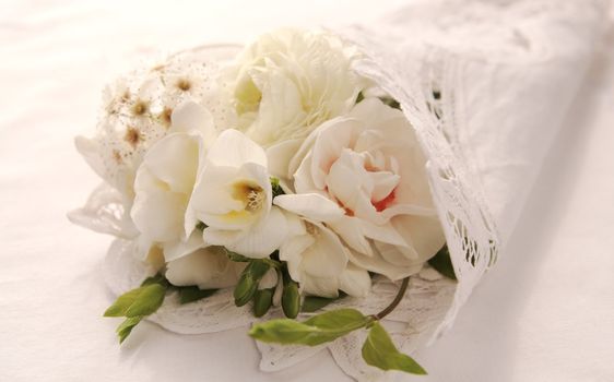 white spring flowers of freesia, daffodil, ranunculus and crabapple blossoms in a lacy cloth