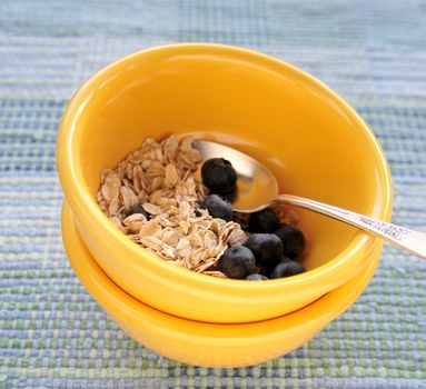 uncooked oatmeal with fresh blueberries in bright yellow bowls