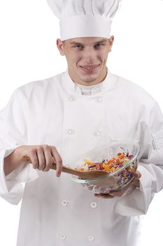 The young chef in uniform and chef's hat in the bowl of salad mixes.
