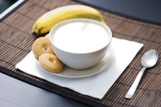 Breakfast with a cup of cappuccino with four biscuits and a banana