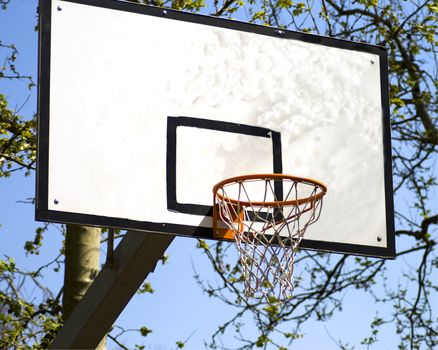 A playground basket for basketball, with blue sky and trees