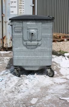 Portrait shot of a waste bin/dumpster set in an industrial type setting with waste material(paper)visible.Printers waste material. Room at base of image.