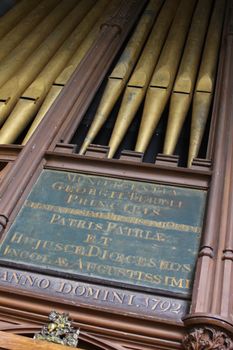 Angled view of brass church organ pipes, with a hand scribed panel in Latin with the dateAnno Domini 1792. located in St.Thoma's Church in Salisbury, Wiltshire.